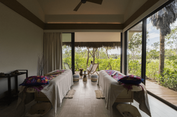 two massage tables in treatment room with jungle views